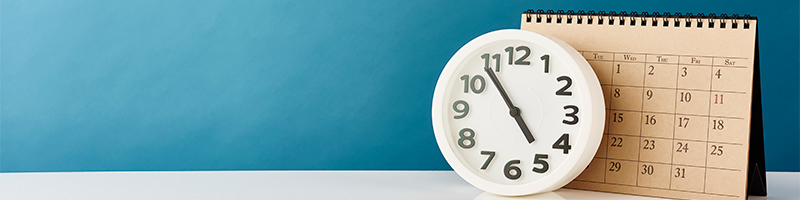 Cadrage sur un calendrier et une horloge appuyés contre un mur bleu