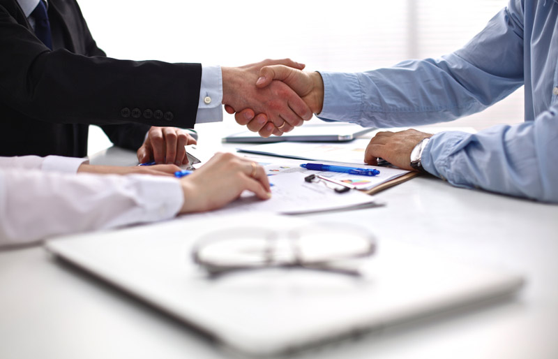An photo of a male and female business professional shaking the hand of a job applicant. 