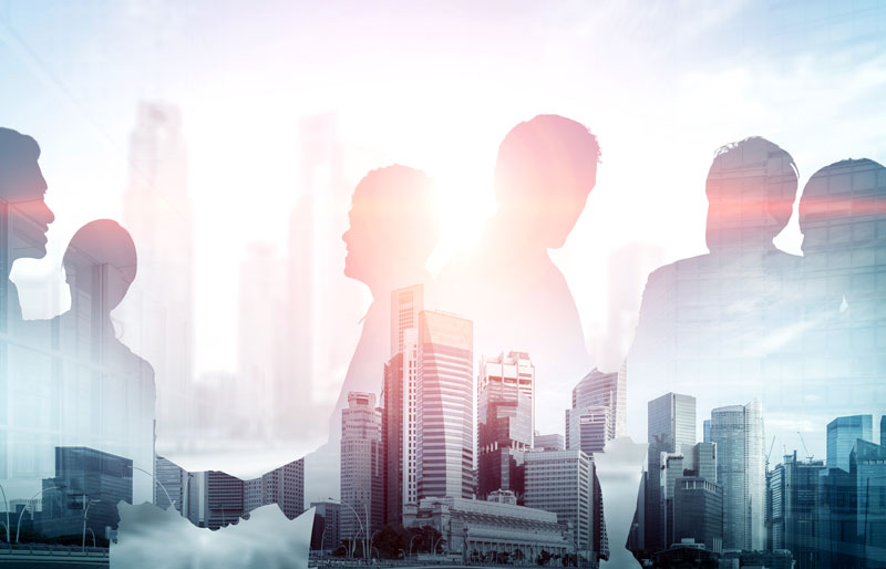 Silhouettes of business people meeting in front of silhouettes of buildings.