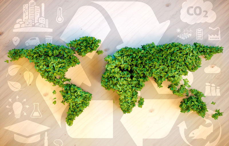 Carte du monde faite de feuilles vertes sur un arrière-plan montrant le symbole du recyclage et d'autres symboles liés à l'environnement.