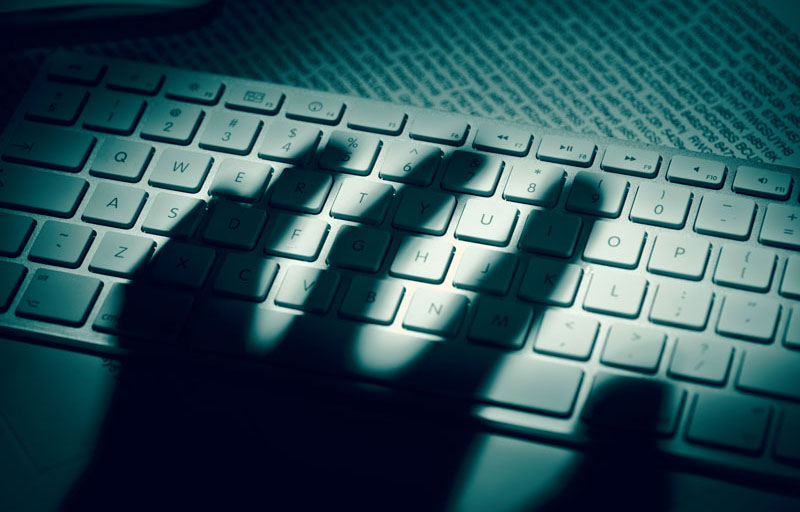 Ombre d'une main sur un clavier d'ordinateur illustrant la fraude.
