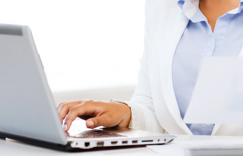 A close crop photo of a female business professional working at her desk on a laptop. 