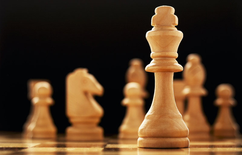 Des pièces d’un jeu d’échecs sont disposées sur un échiquier, dont le roi au premier plan.