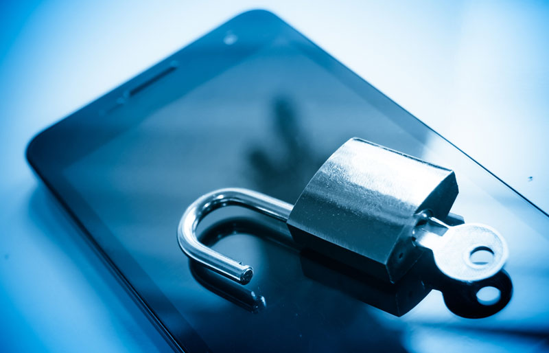 A close-up image of an iPhone with an open padlock with a key inserted resting on the screen.