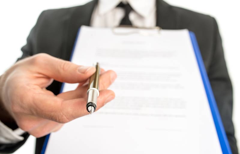 Un homme d’affaires ou agent commercial remet un contrat attaché à une planchette à pince et tend un stylo à plume pour la signature du contrat.