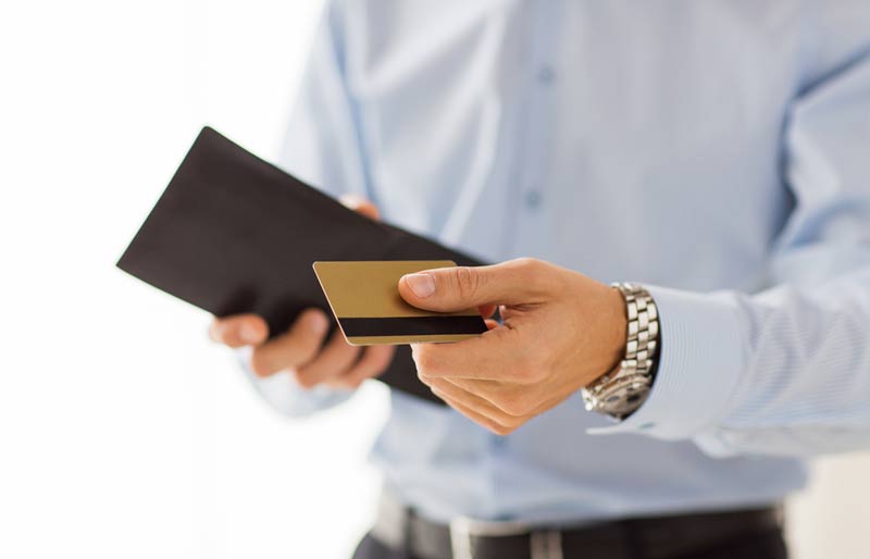A business professiona holding an open wallet and presenting a gold rewards card.