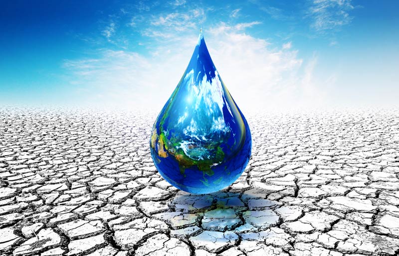 Une goutte d’eau représentant la Terre tombe sur un sol desséché.