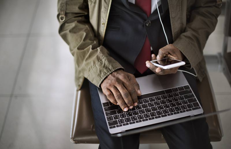 Un directeur numérique, nouveau professionnel en demande, travaille sur son ordinateur portable, cellulaire à la main. 