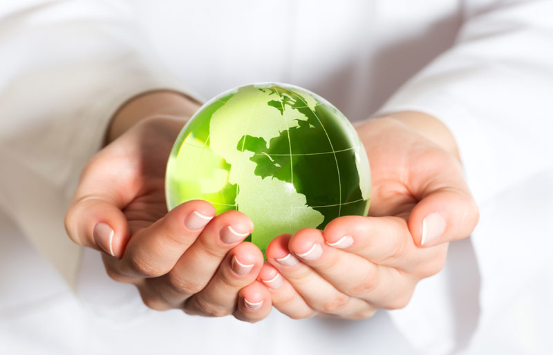 Woman holding green coloured globe in her hands