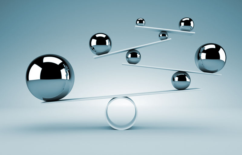 A balancing act concept image using Teeter Totters and different sized ball bearings. 