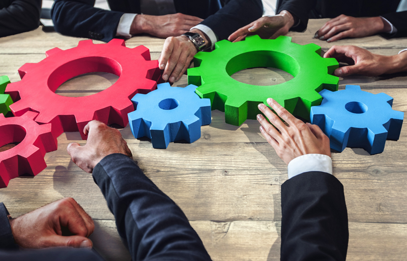 A group of business people examining the model of several cogs connected together