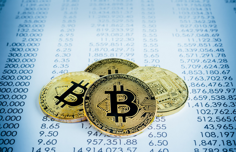 Quatre pièces de monnaie avec le logo de Bitcoin sont déposées sur des documents financiers.