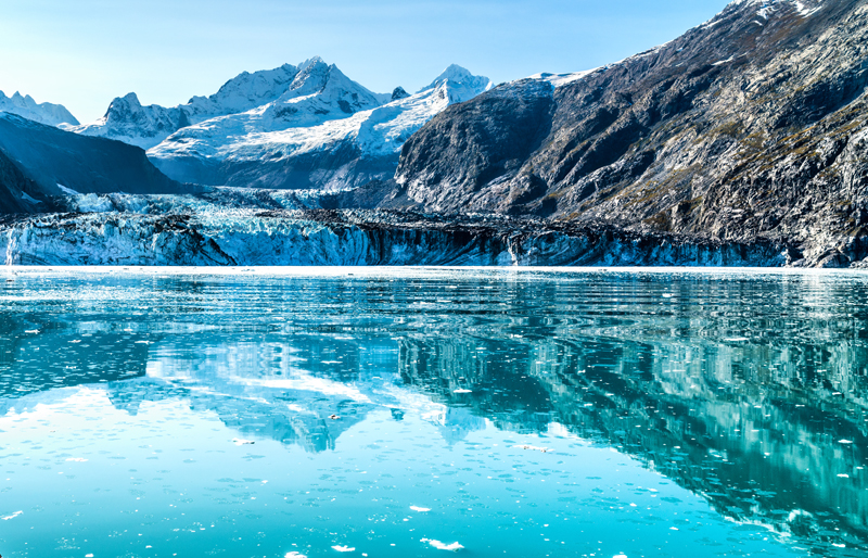 Des montagnes enneigées dans un paysage d'hiver, et une étendue d'eau bleue et cristalline.
