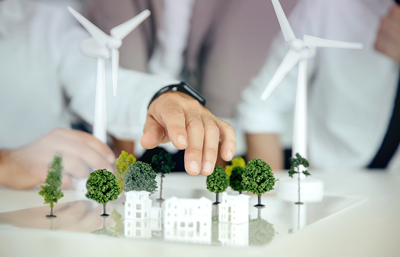 two people urban planning using windmills and miniature models of trees and buildings