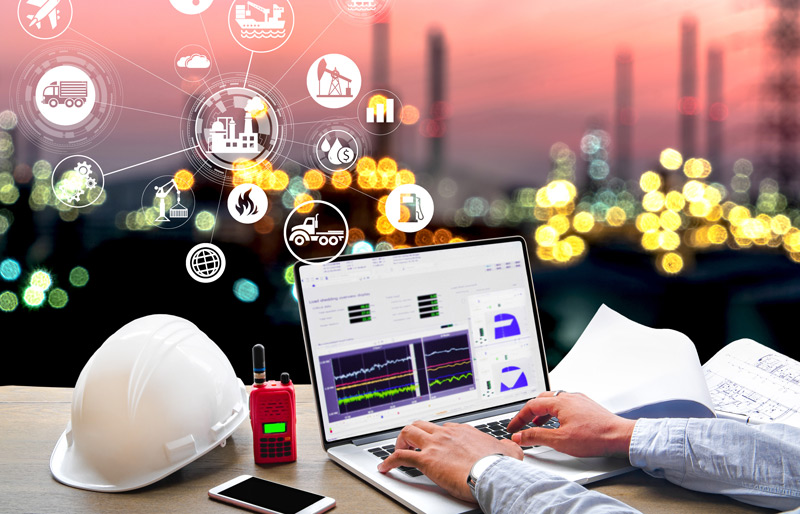 Picture of a business person working on a laptop with an oil refinery in the background and technology icons superimposed over the image.