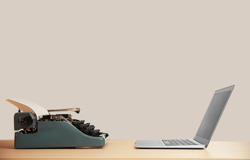 Cadrage sur une machine à écrire et un ordinateur portable posés face à face sur un bureau.