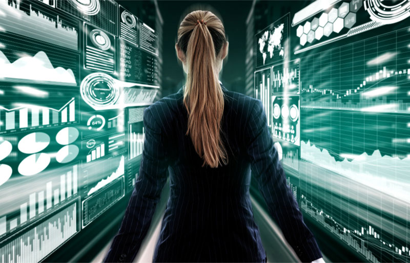 Woman walking down a narrow corridor with electronic data walls on each side.