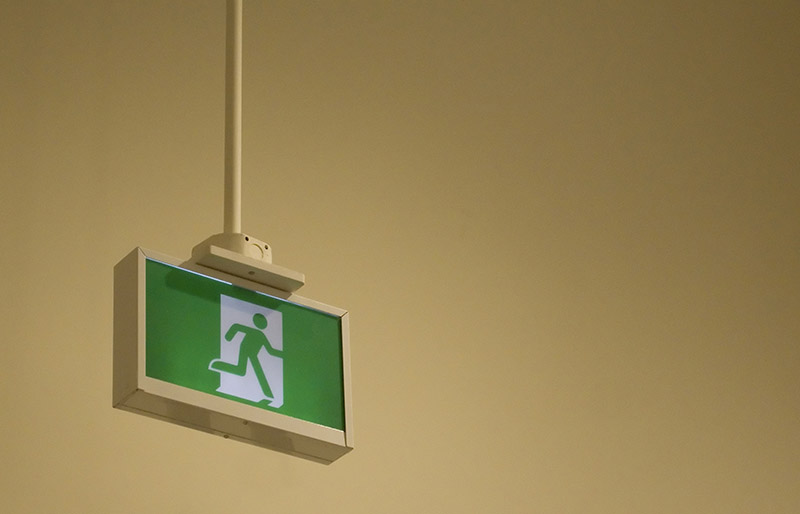 Cadrage d’une affiche sur fond vert symbolisant une personne courant vers une sortie d’urgence
