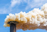 Gros plan sur une cheminée industrielle qui dégage de la fumée polluante