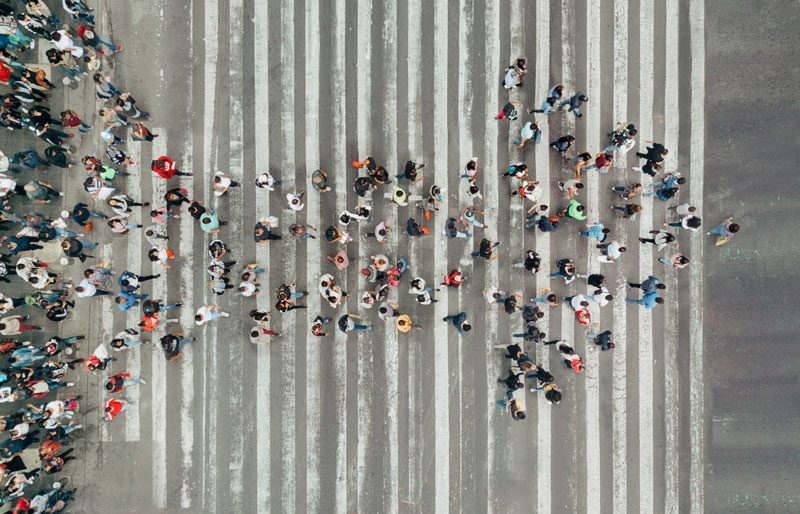 Aerial view of a crowd of people crossing the street in the formation of an arrow.