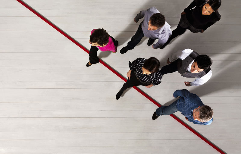 Aerial view of a six business people walking forward and stepping over a red line.
