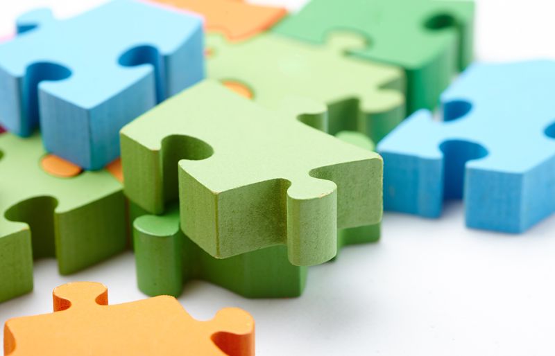 Brightly coloured jigsaw puzzle pieces on white surface.