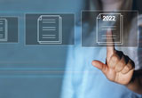 Image d'une rangée de documents virtuels affichés à l'écran et dont un doigt est pointé sur un seul.