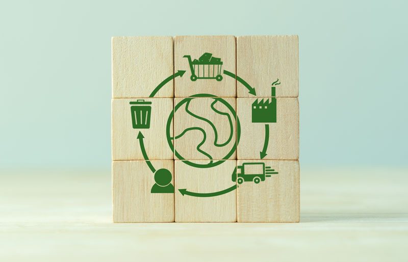 Wooden block puzzle assembled to form an image of planet earth surrounded by sustainability icons.