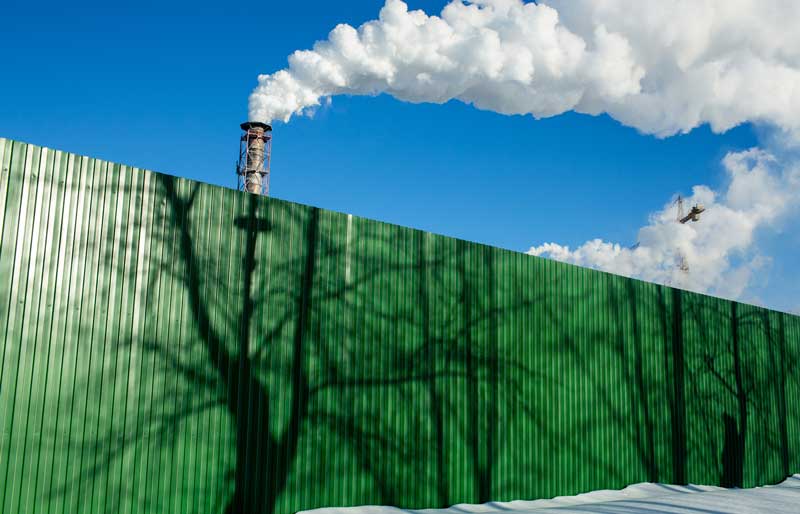 Green wall showing tops of smokestacks behind.