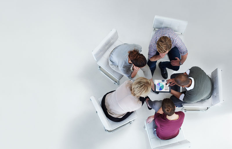 Top view of group of business people working around a small table.