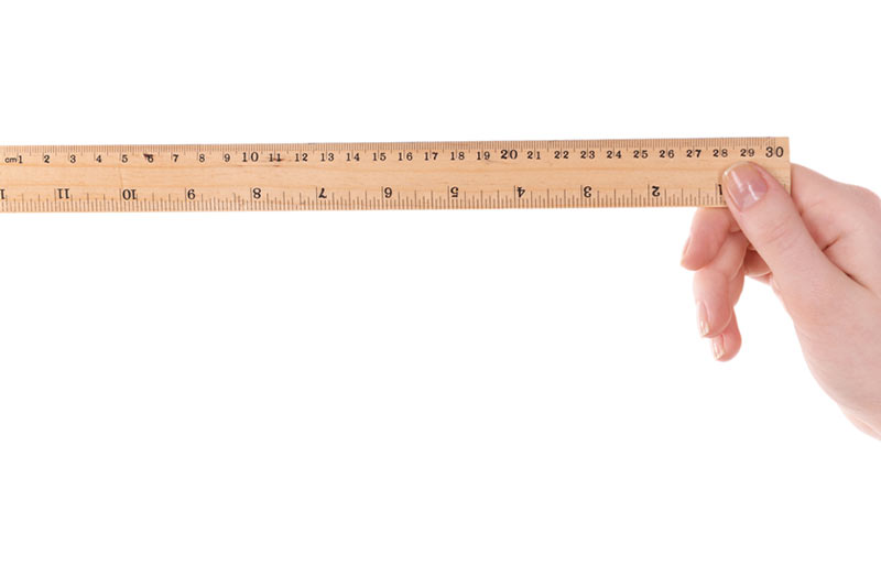 A hand holding up a wooden ruler. 