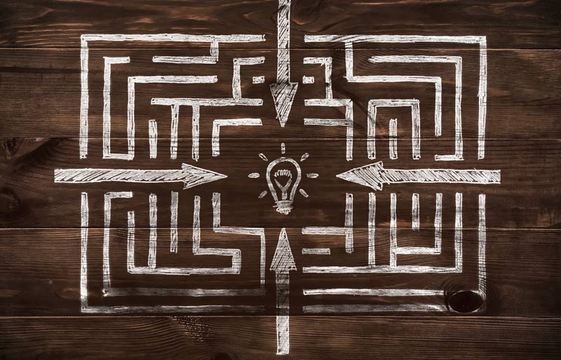 A drawn maze with directions pointing to the centre. A light bulb is in the centre. 