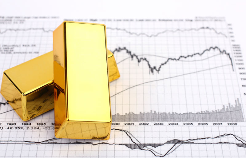 Gold bars sitting on printed financial charts