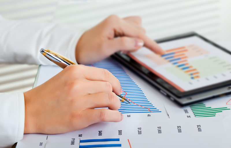A cropped image of a female business professional working on financials. 