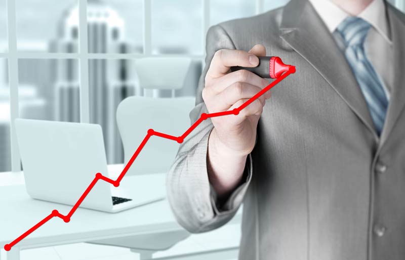 Male accountant drawing a red line graph on glass. 