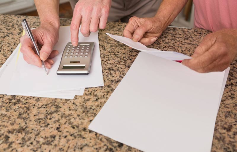 Un couple d’aînés calcule ses factures sur le comptoir de la cuisine.