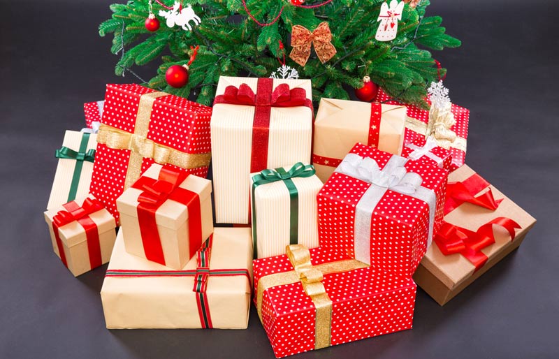 Des paquets cadeaux sont posés au pied d’un sapin de Noël.