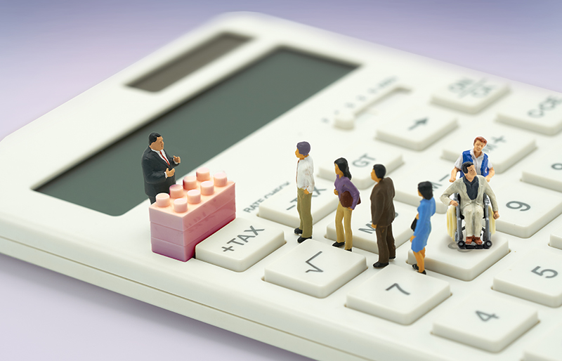 Miniature toy people gather atop a calculator for a presentation.
