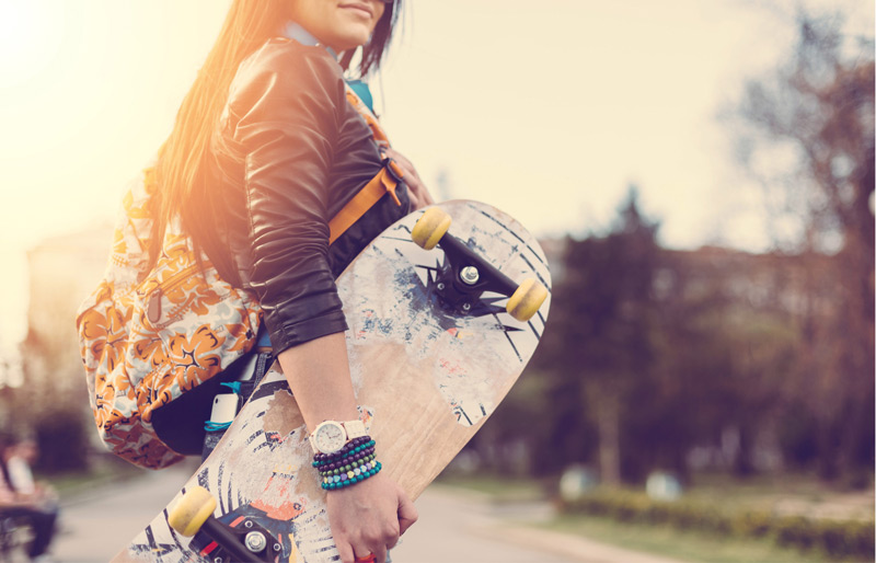 Woman standing outside holding a skateboard.