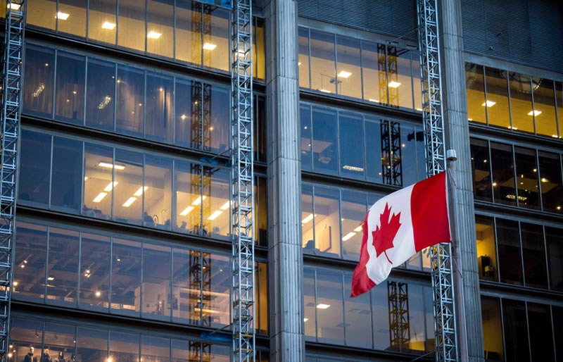 Les propositions du ministère des Finances du Canada sont illustrées par l’image d’un drapeau canadien qui flotte au vent devant un édifice moderne.