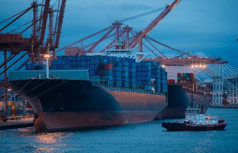 La participation du Canada au commerce international est illustrée par l’image de deux navires transportant des conteneurs, amarrés à un port.  