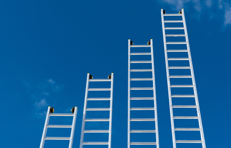 Four ladders reaching up in to the sky at different heights, resembling a business bar chart