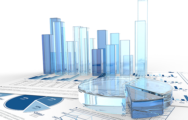 Various business graphs made of transparent coloured glass, sitting on various business documents