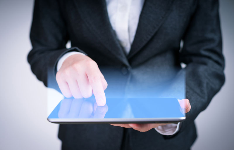 Le webinaire de l’IAASB sur les changements concernant le contrôle qualité est illustré par l’image d’une personne en complet tenant une tablette électronique de laquelle émane une lumière bleue.