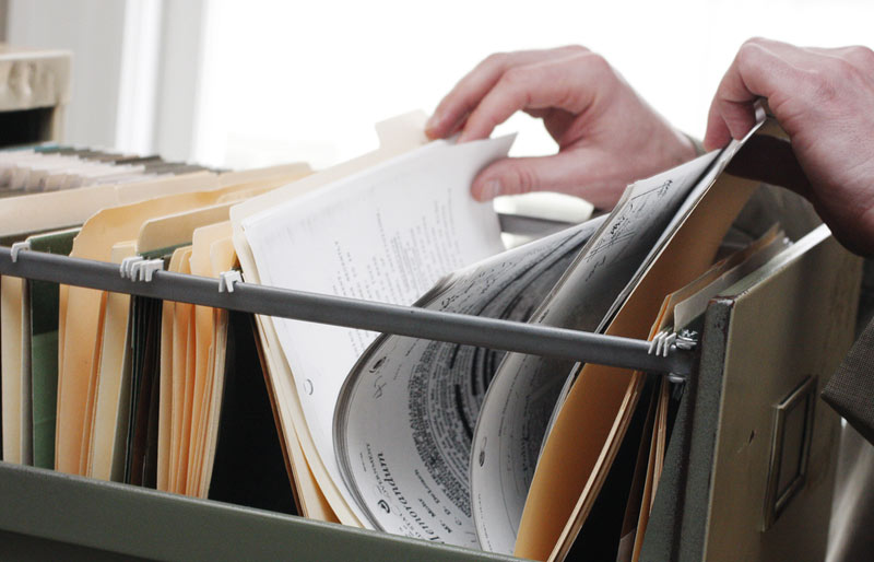 Businessman sifting through documents in file folder in filing cabinet