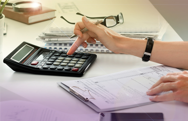 Woman using calculator, while doing taxes at desk