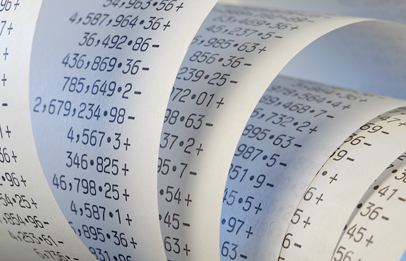 Gros plan sur un rouleau de papier pour calculatrice rempli de nombres.