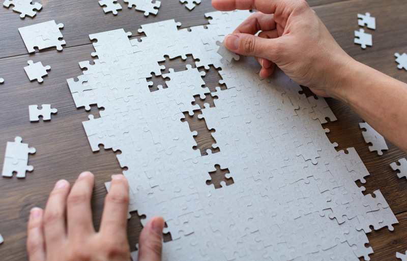 Les mains d’une personne complètent un puzzle où les pièces manquantes forment un point d’interrogation