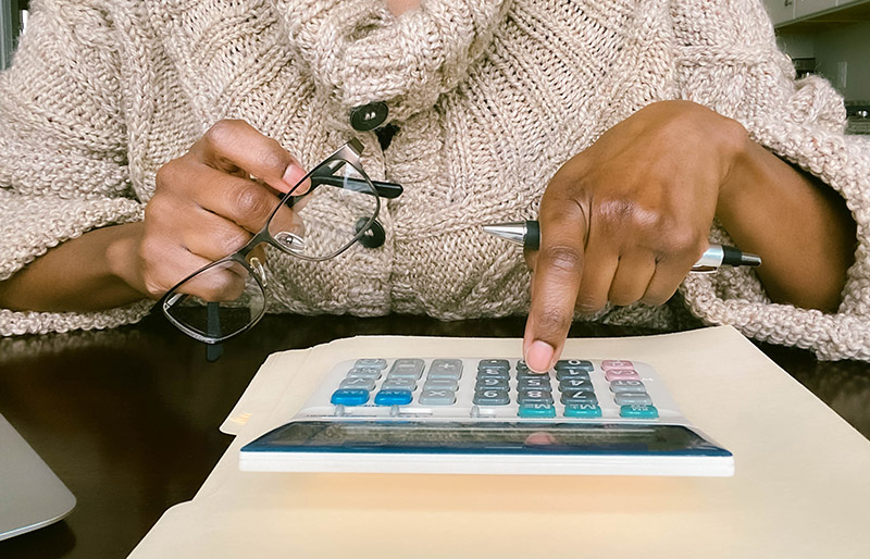 Cadrage sur les mains d’une femme assise à un bureau qui utilise une calculatrice