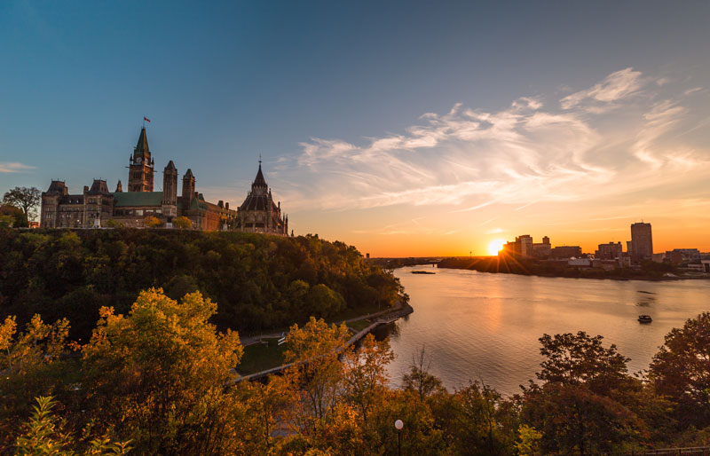 Édifices du Parlement d'Ottawa et rivière au coucher du soleil.